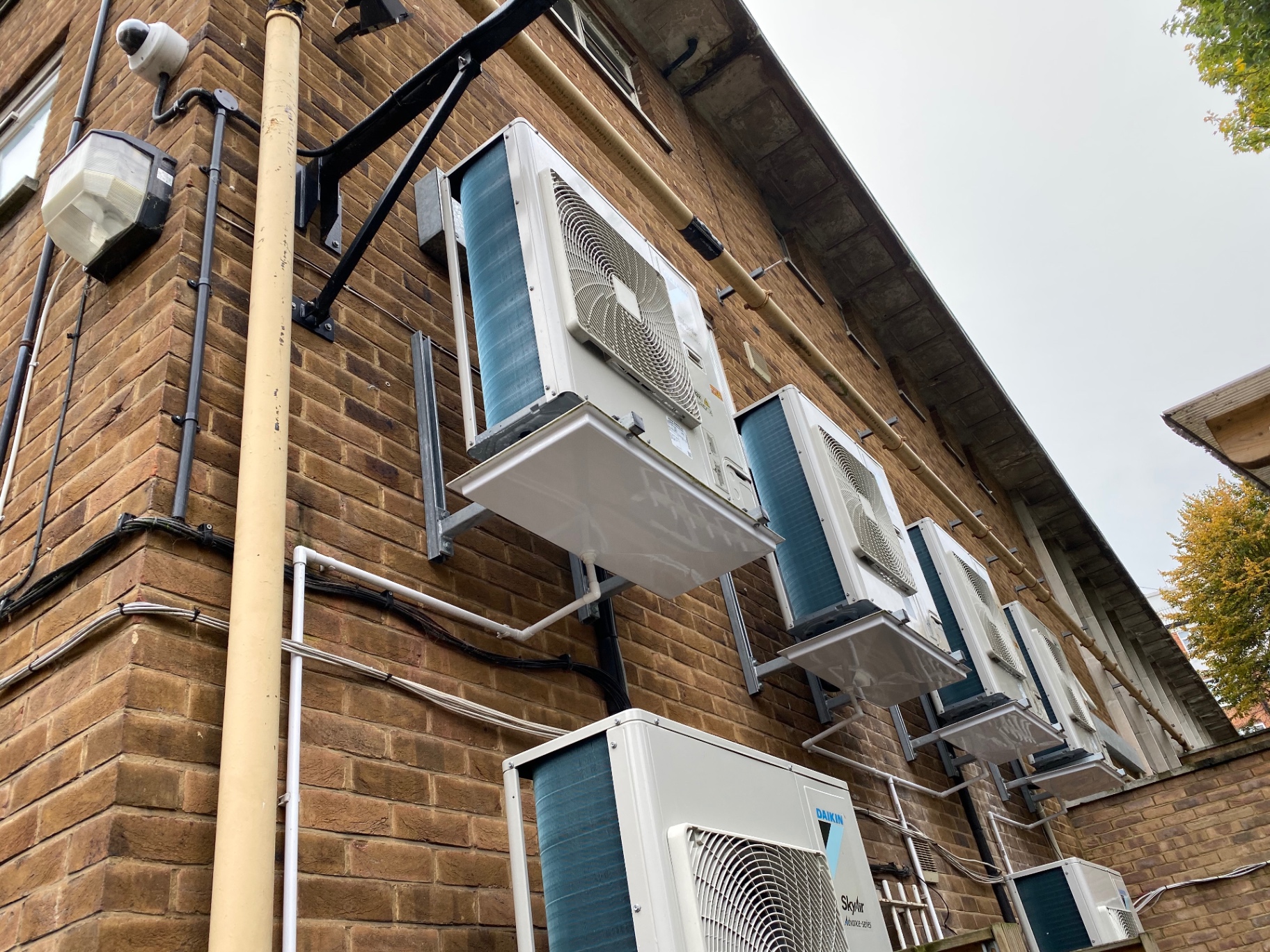 Stacked Daikin Sky Air condensers on a brick facade